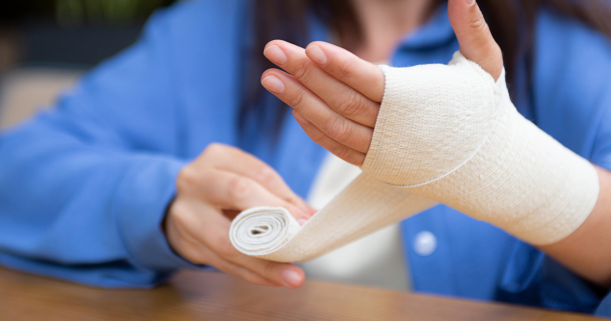 Close up of person wrapping arm with white gauze. 