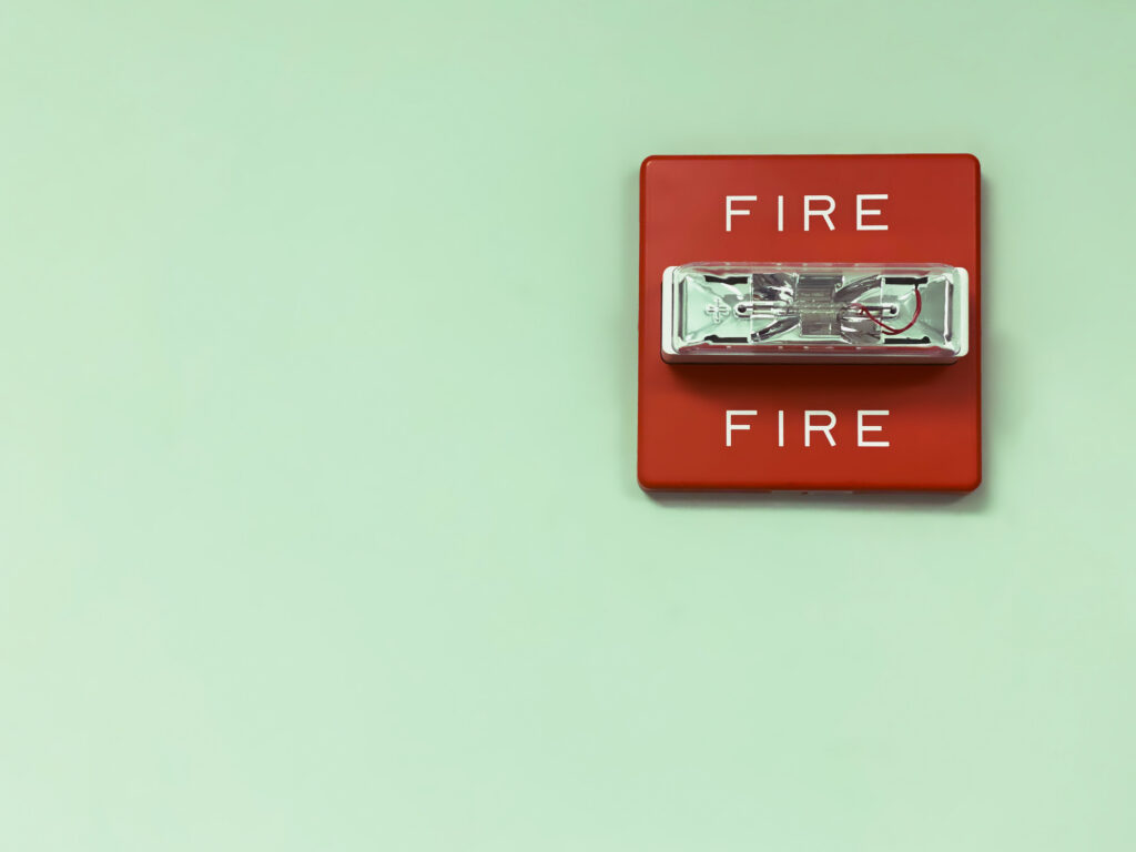 A business fire safety alarm system is shown on a light green wall.